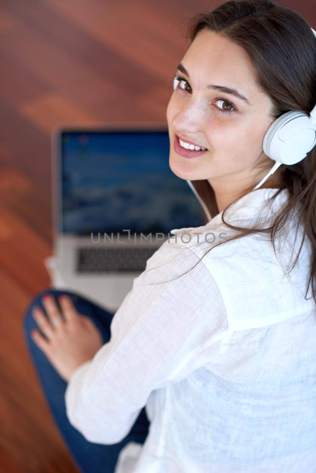 beautiful young woman relax and work on laptop computer modern  home office while listening musin on white headphones