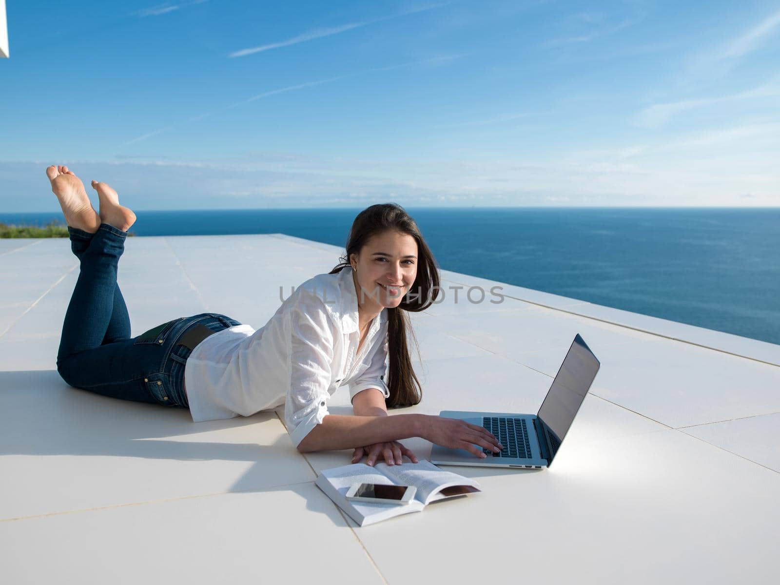 beautiful young woman relax and work on laptop computer  and read book at modern  home