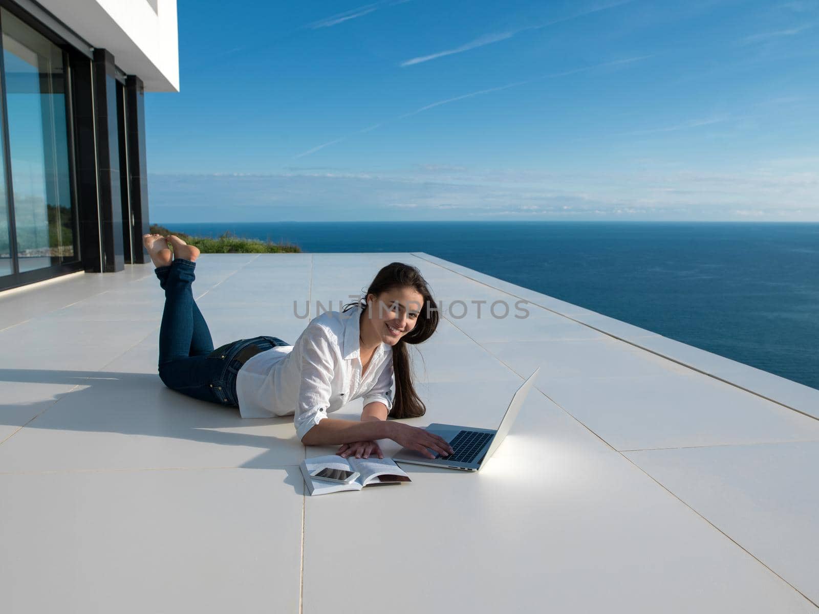 beautiful young woman relax and work on laptop computer  and read book at modern  home