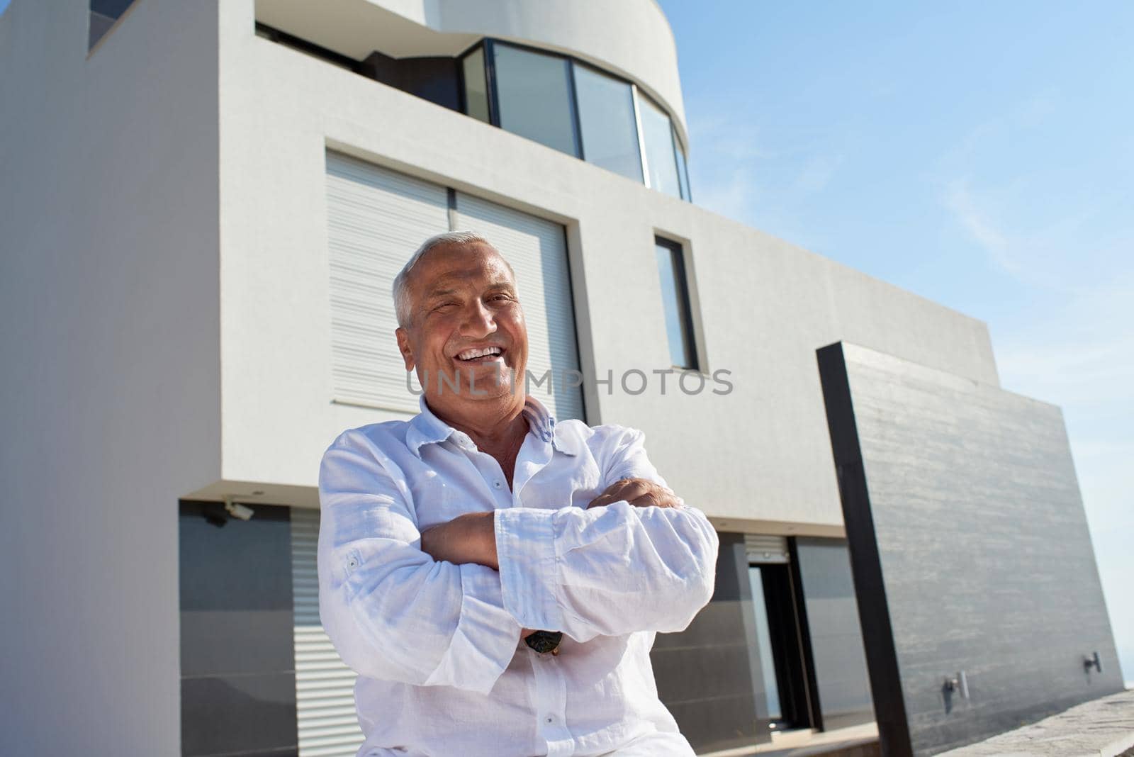 senior man in front of modern home by dotshock