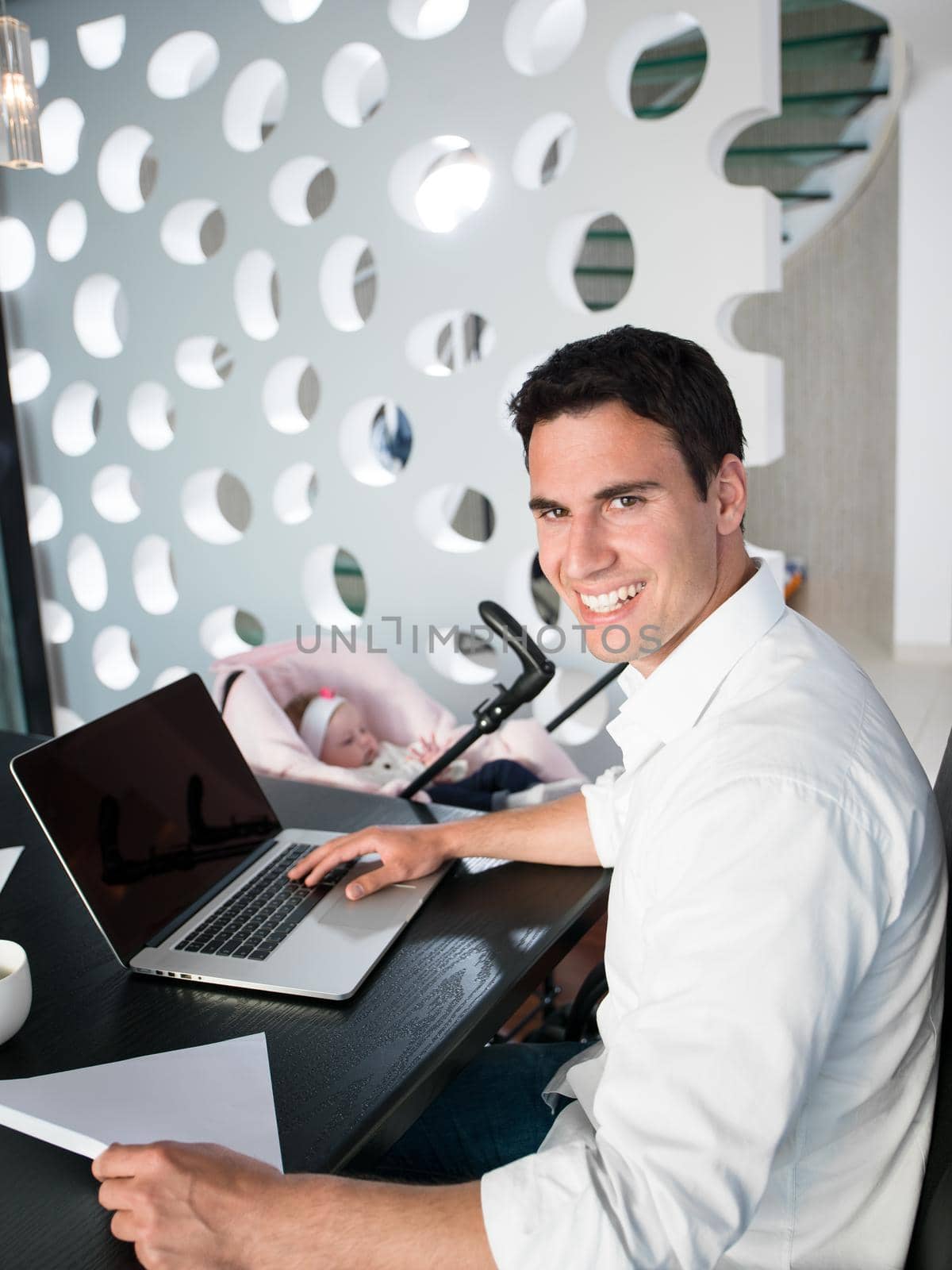 young man parent working on laptop computer at home office and take care of baby