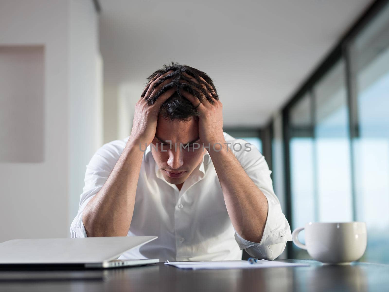 frustrated young business man working on laptop computer at home by dotshock