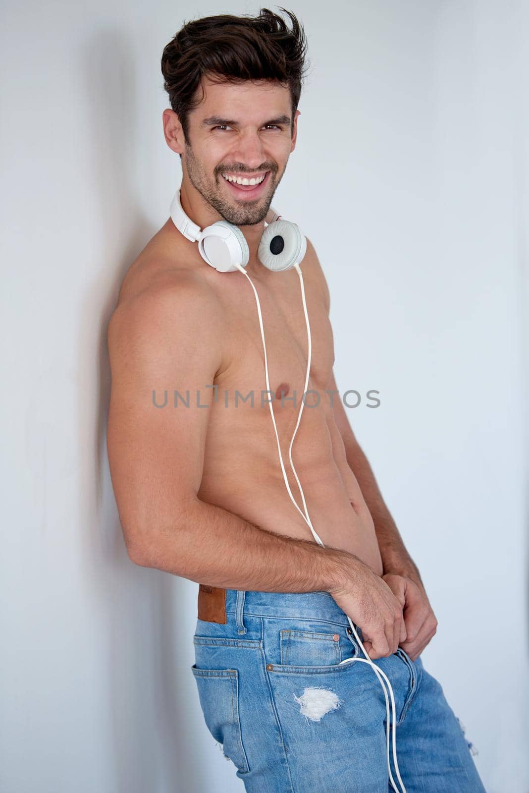 handsome young man listening music on headphones at modern home over  white wall and standing on hands
