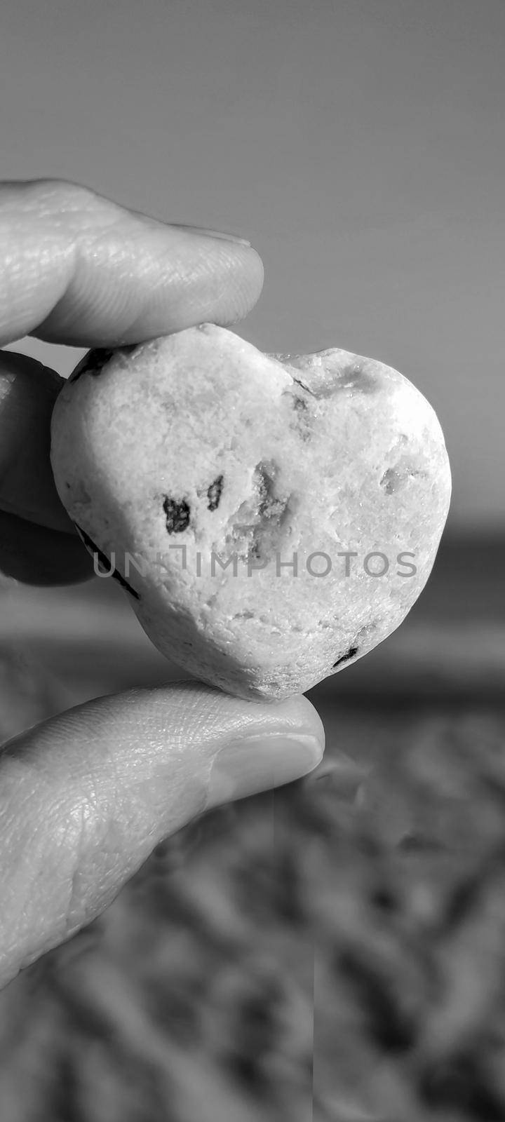 Stone heart in hand, close-up. Desktop for phone screensaver. Black and white