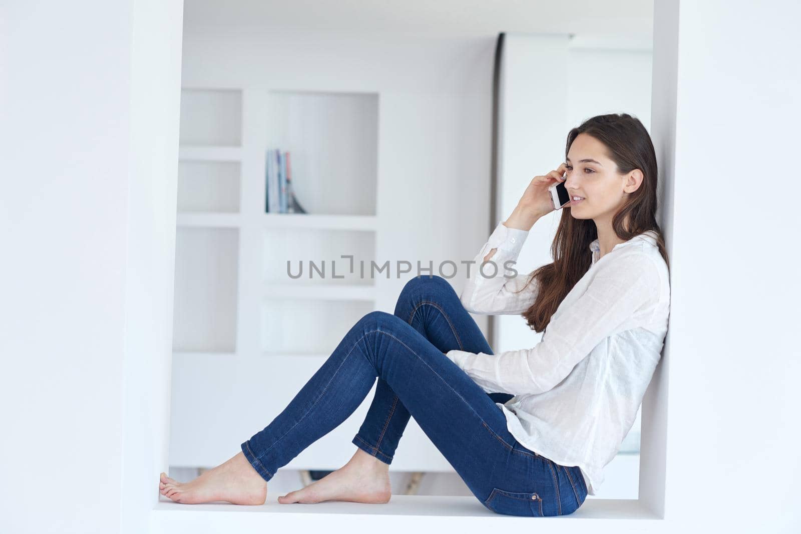 young woman using cellphone at home by dotshock
