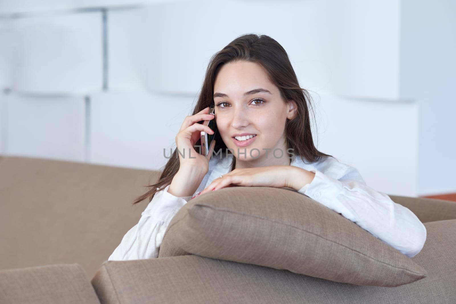 happy young woman using cellphone at home and relaxing