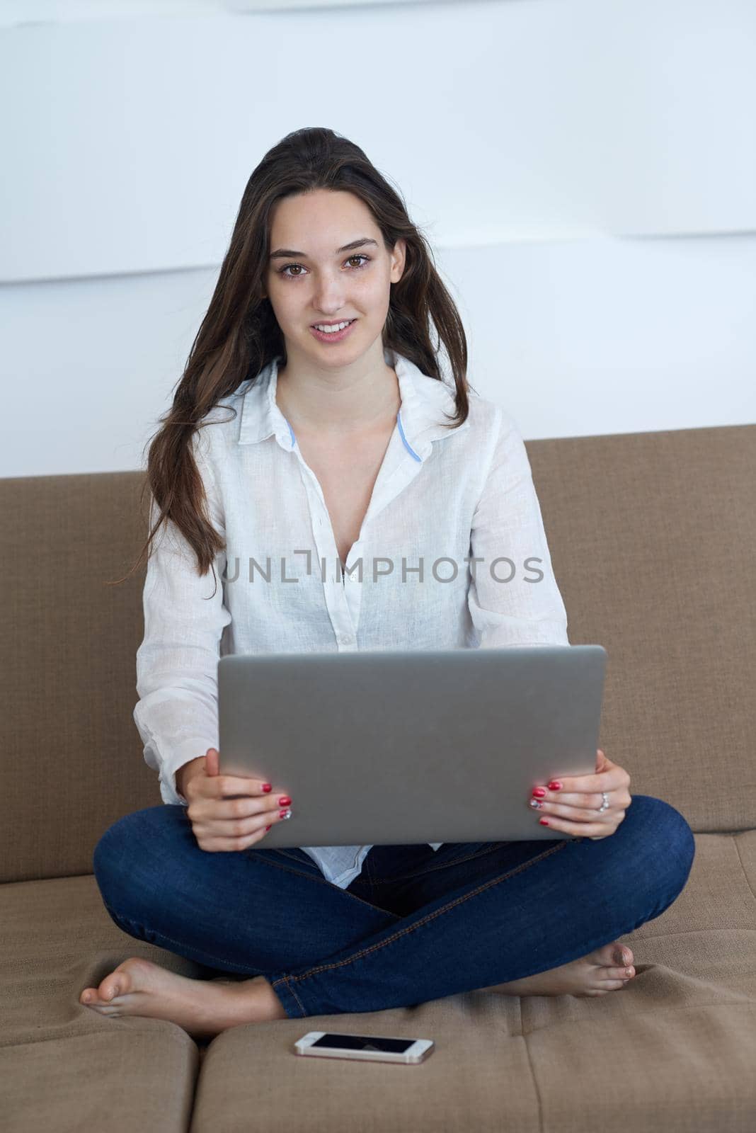 beautiful young woman relax and work on laptop computer modern  home office while listening musin on white headphones