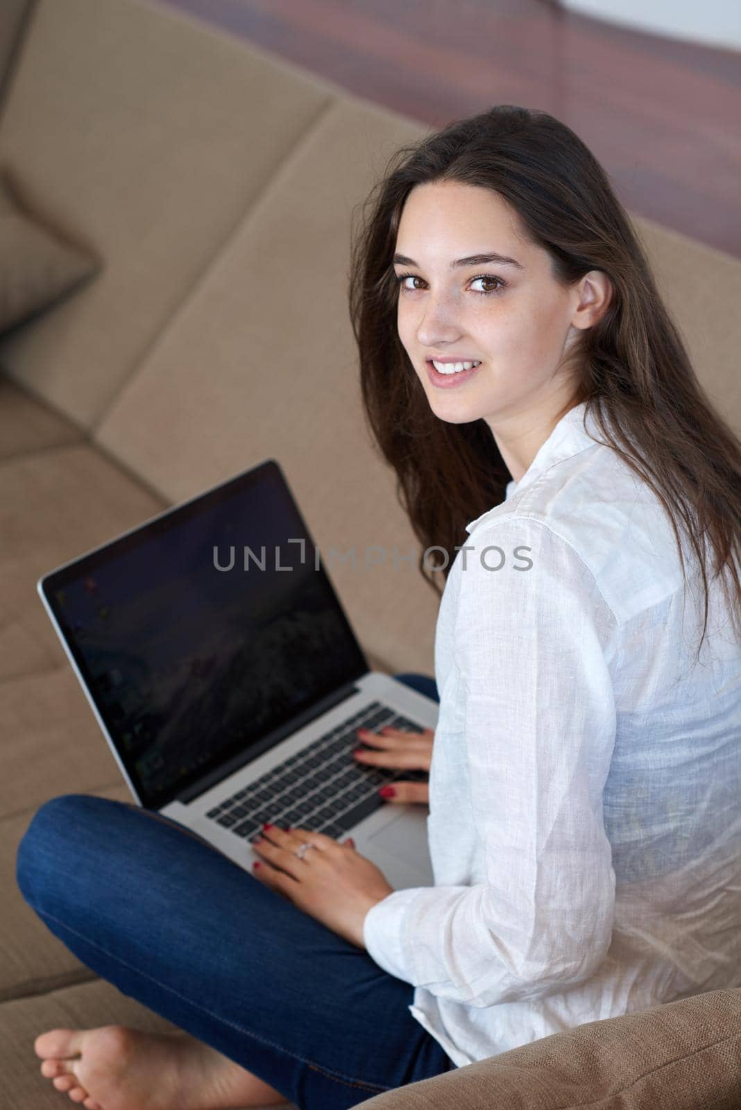 beautiful young woman relax and work on laptop computer modern  home office while listening musin on white headphones