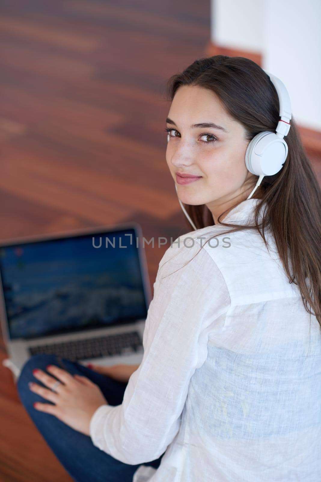 beautiful young woman relax and work on laptop computer modern  home office while listening musin on white headphones