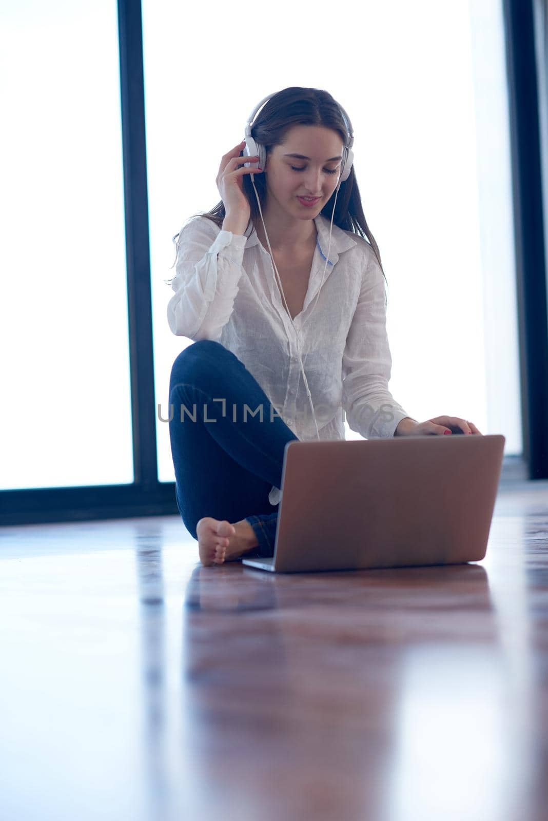 beautiful young woman relax and work on laptop computer modern  home office while listening musin on white headphones