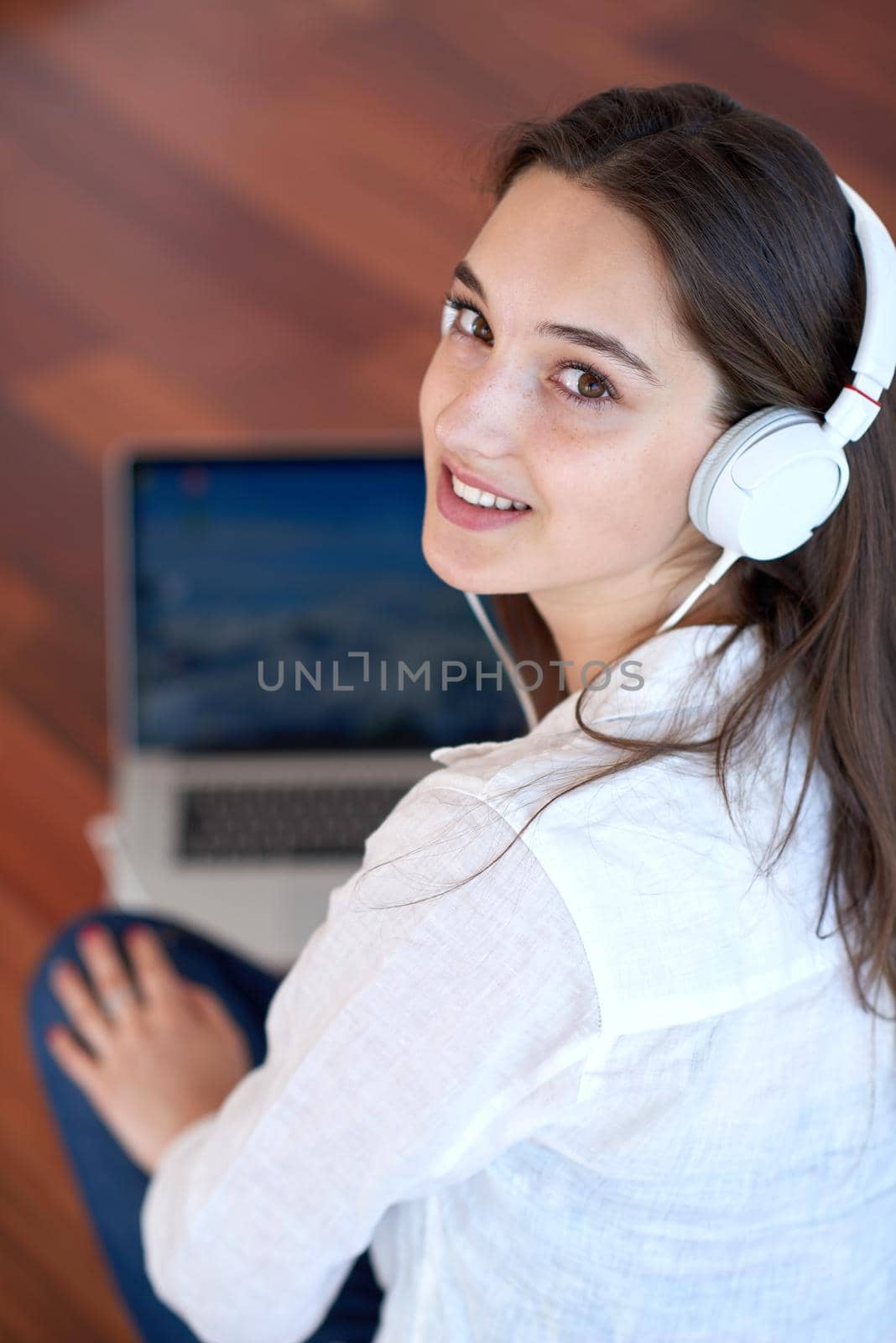 beautiful young woman relax and work on laptop computer modern  home office while listening musin on white headphones