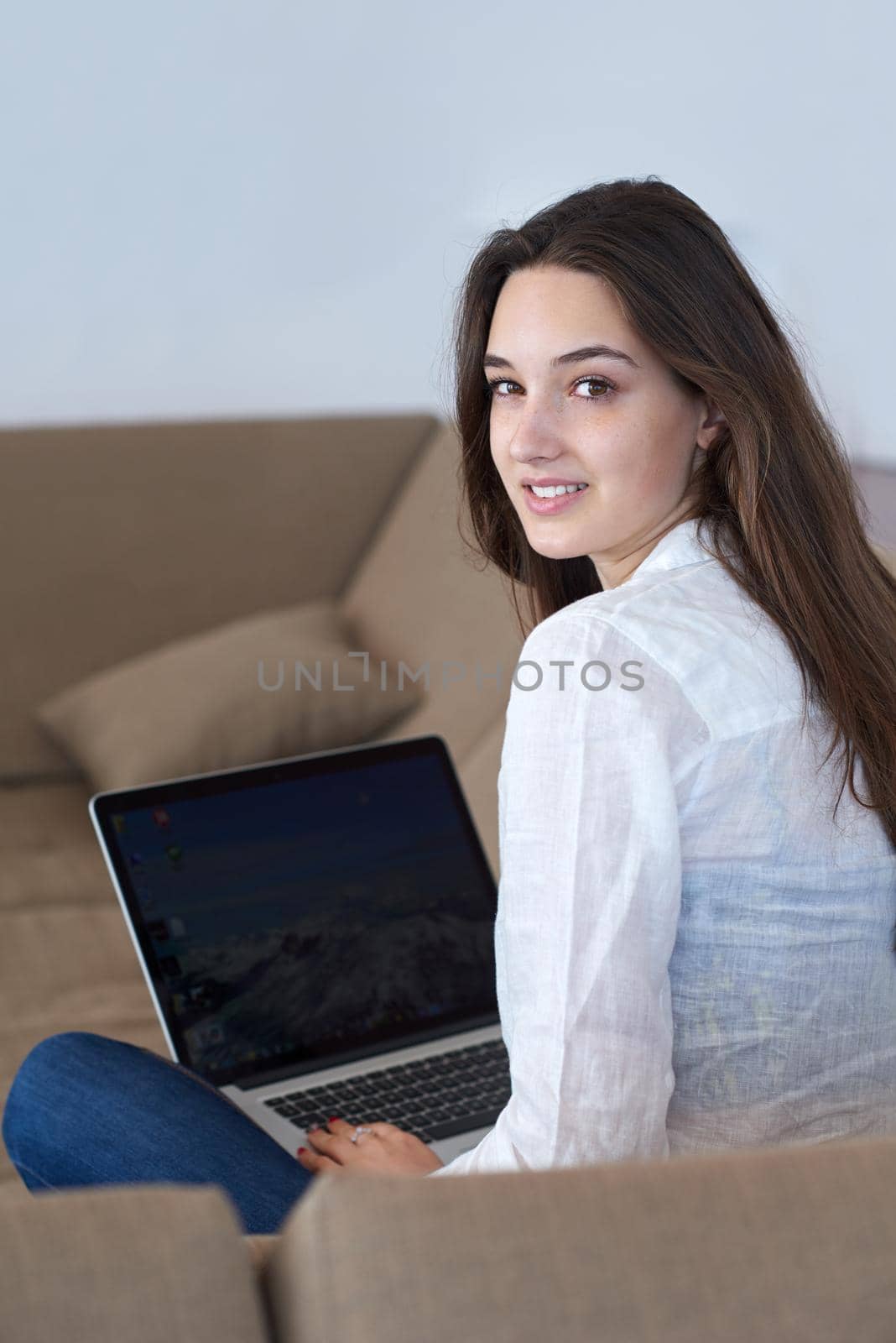 beautiful young woman relax and work on laptop computer modern  home office while listening musin on white headphones