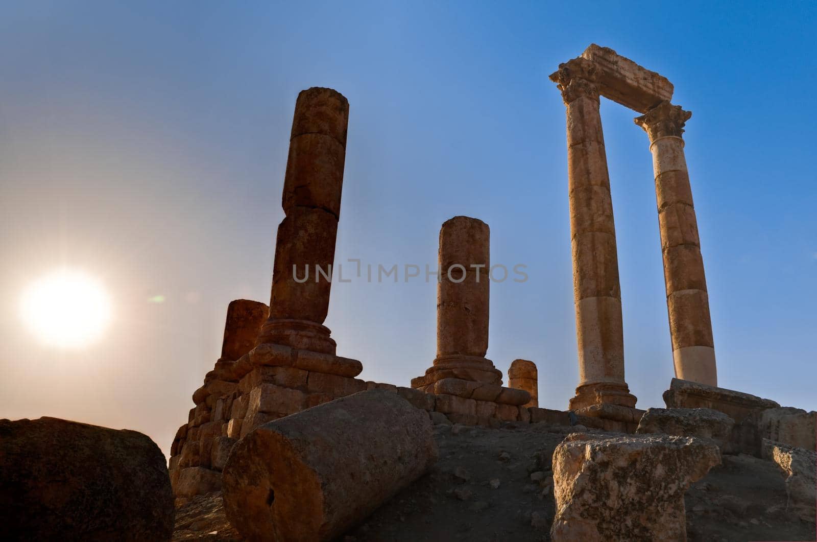 ancient ruins with sun and sunset sky in background (Temple of Hercules in Amman, Jordan)