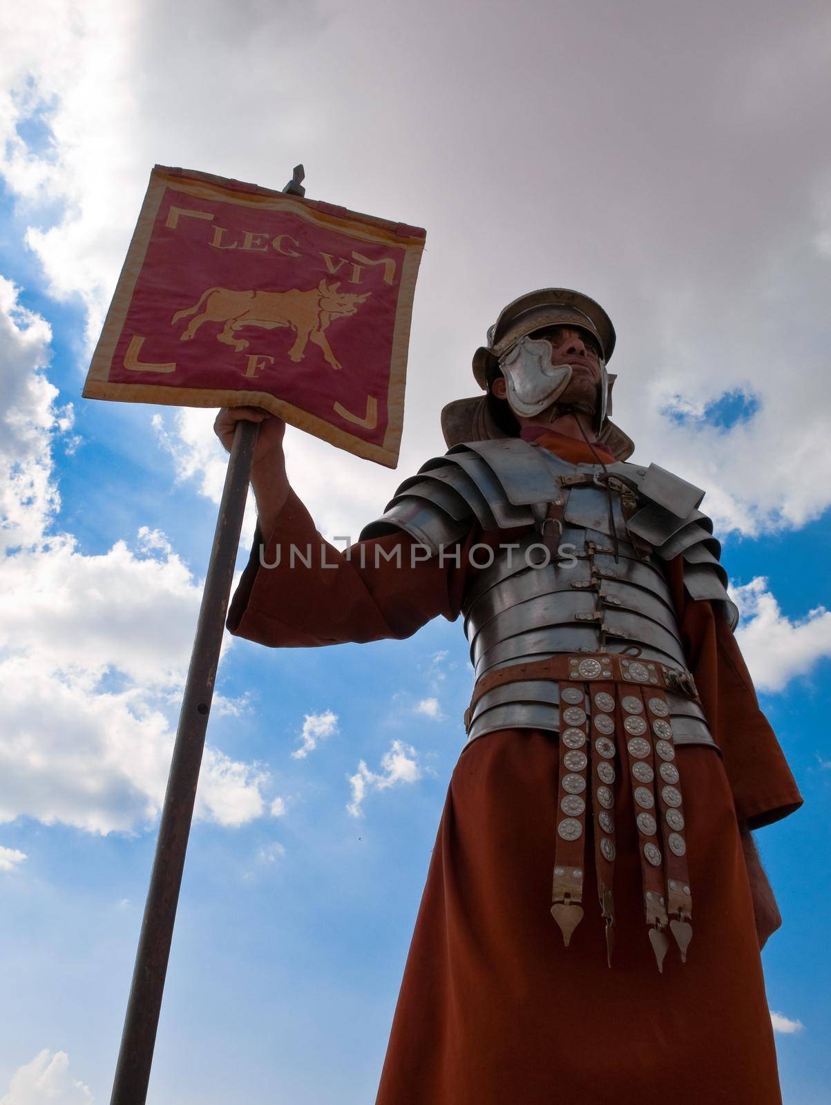 roman warrior standing with flag of his legion with blue cloudy sky in background