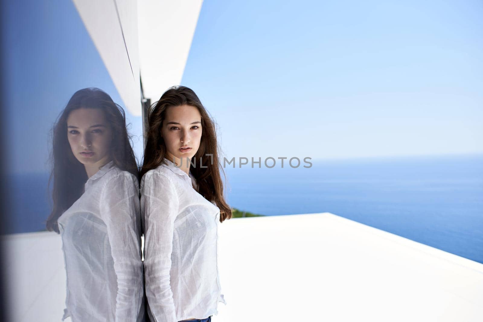 relaxed young beautiful woman in front of luxury modern home villa  on balcony on sunny day