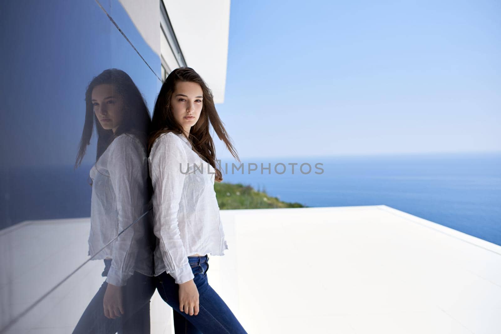 relaxed young beautiful woman in front of luxury modern home villa  on balcony on sunny day