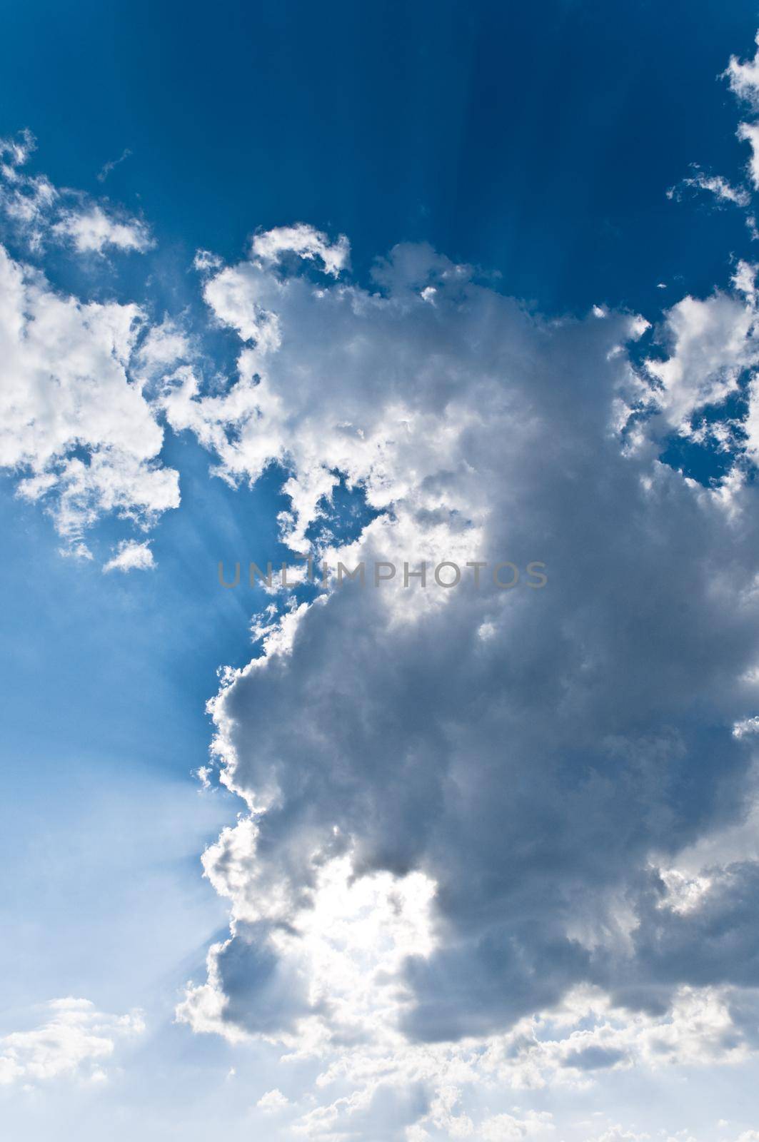 white cloud in blue sky lighted from behind by the sun