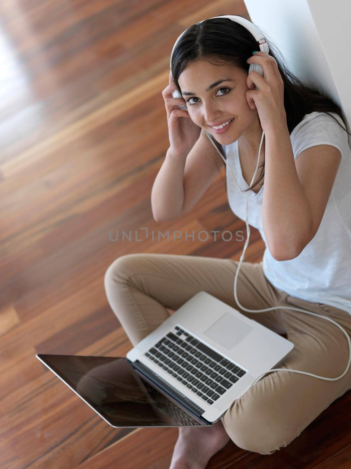 beautiful young woman relax and work on laptop computer modern  home office while listening musin on white headphones