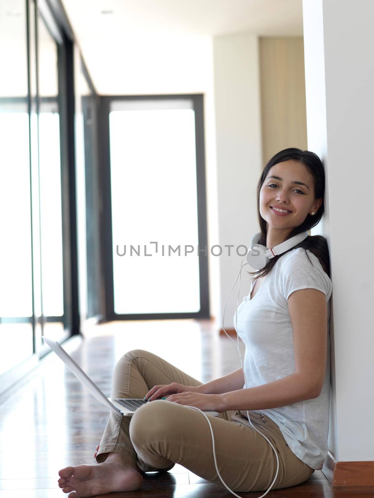 beautiful young woman relax and work on laptop computer modern  home office while listening musin on white headphones