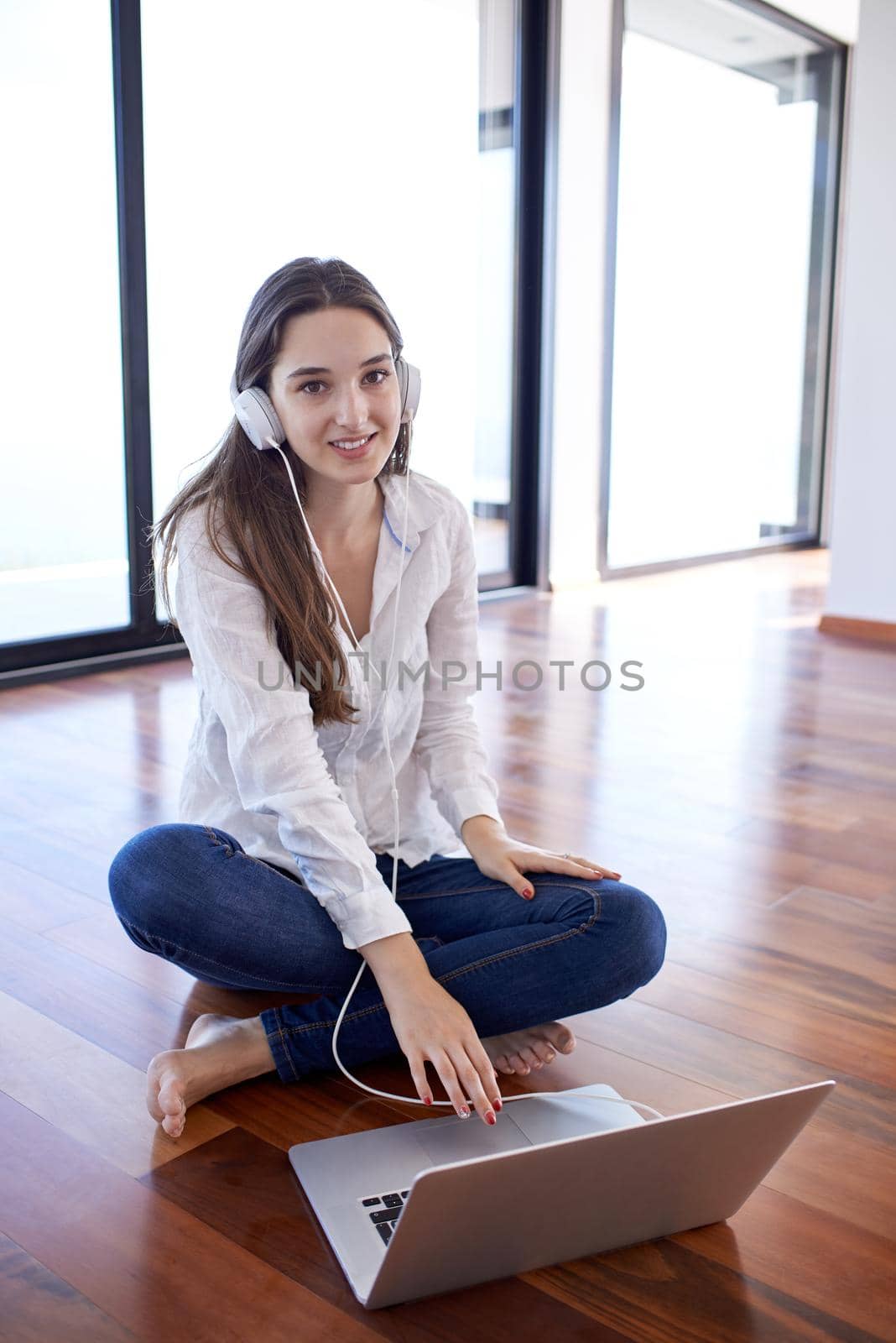 beautiful young woman relax and work on laptop computer modern  home office while listening musin on white headphones