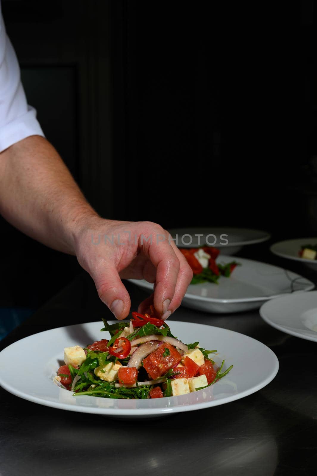 A chef is preparing a plate with fresh salad.