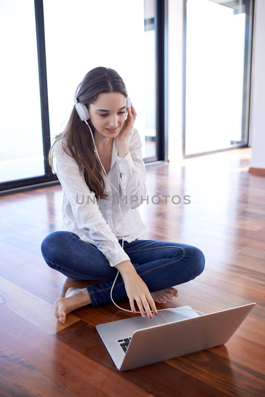 relaxed young woman at home working on laptop computer by dotshock