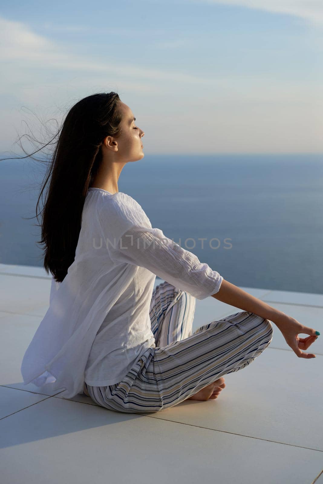 young woman practice yoga meditaion on sunset with ocean view in background