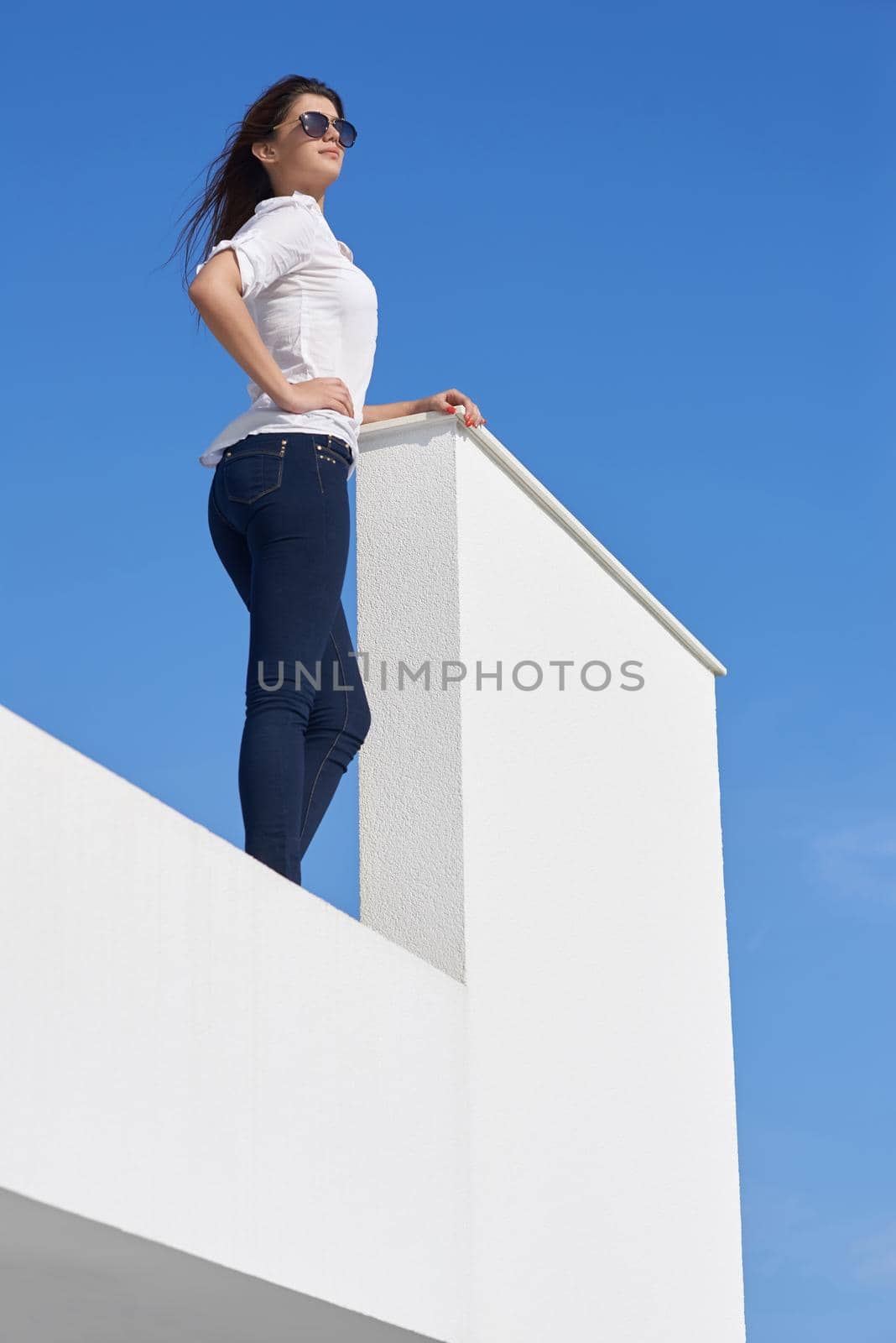 relaxed young beautiful woman in front of luxury modern home villa  on balcony on sunny day