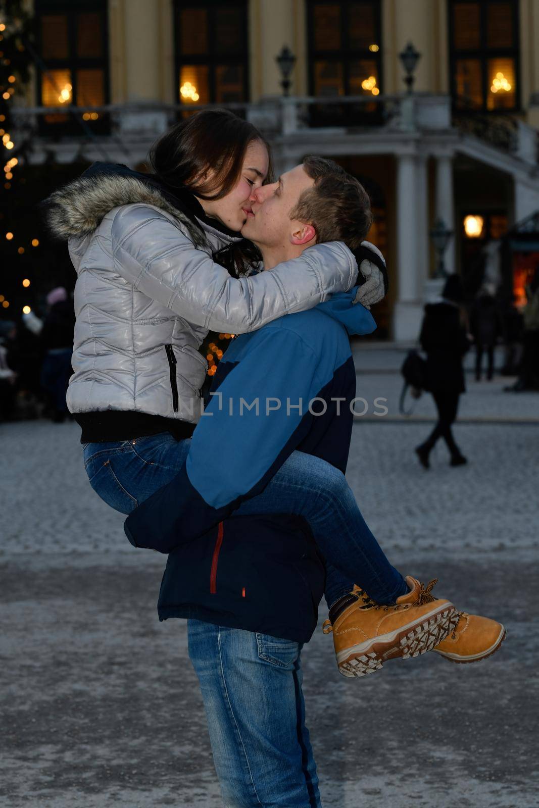 A young couple in love hugs and kisses at the Christmas market.