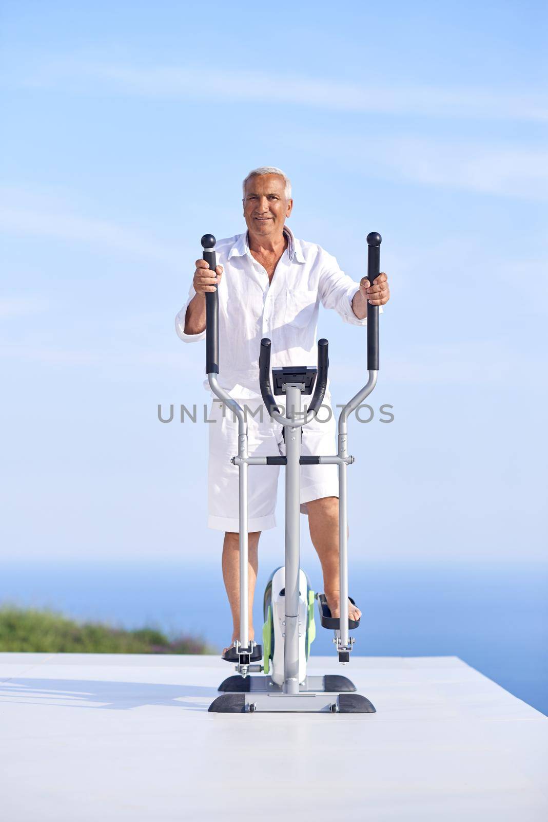 healthy senior man working out on gym treadmill machine at modern home terace with ocean view