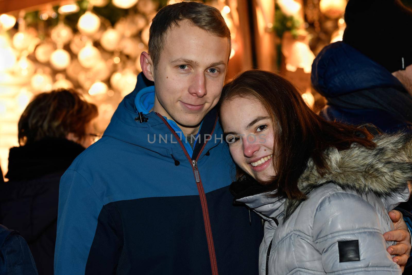 A young couple in love hugs at the Christmas market.