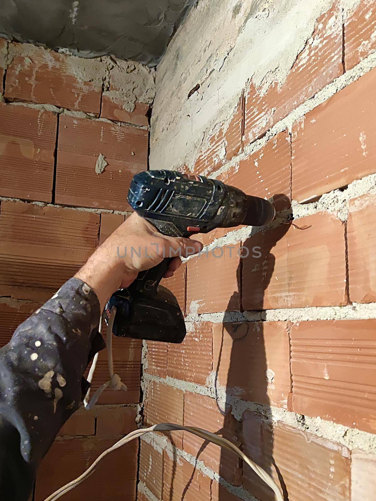 male hand with drill drills brick wall renovation by Annado