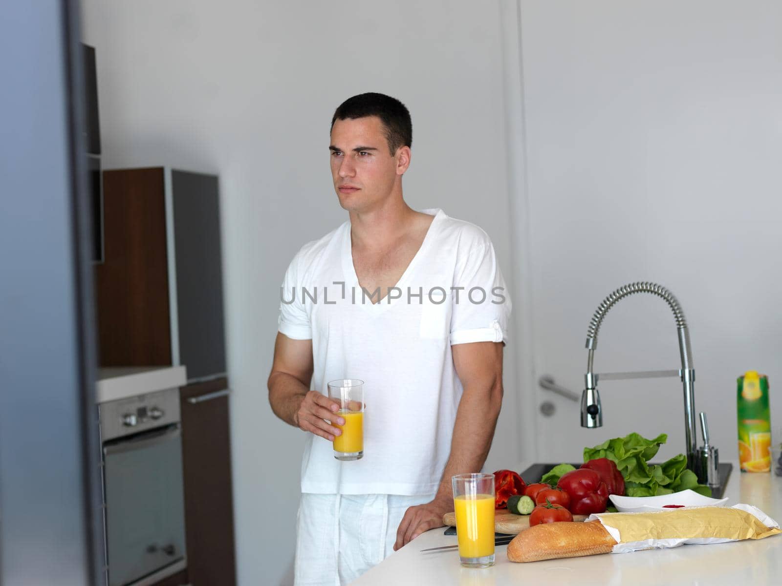 Handsome man cooking at home preparing salad in kitchen.