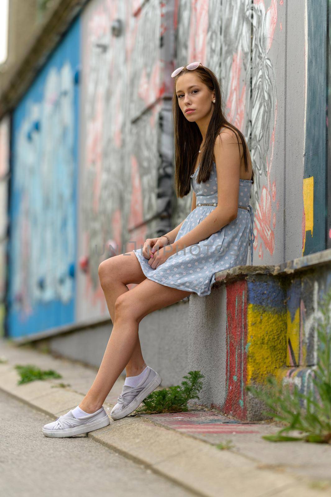 A portrait of a pretty young woman, taken in a city in the summer, is obviously waiting for her boyfriend.