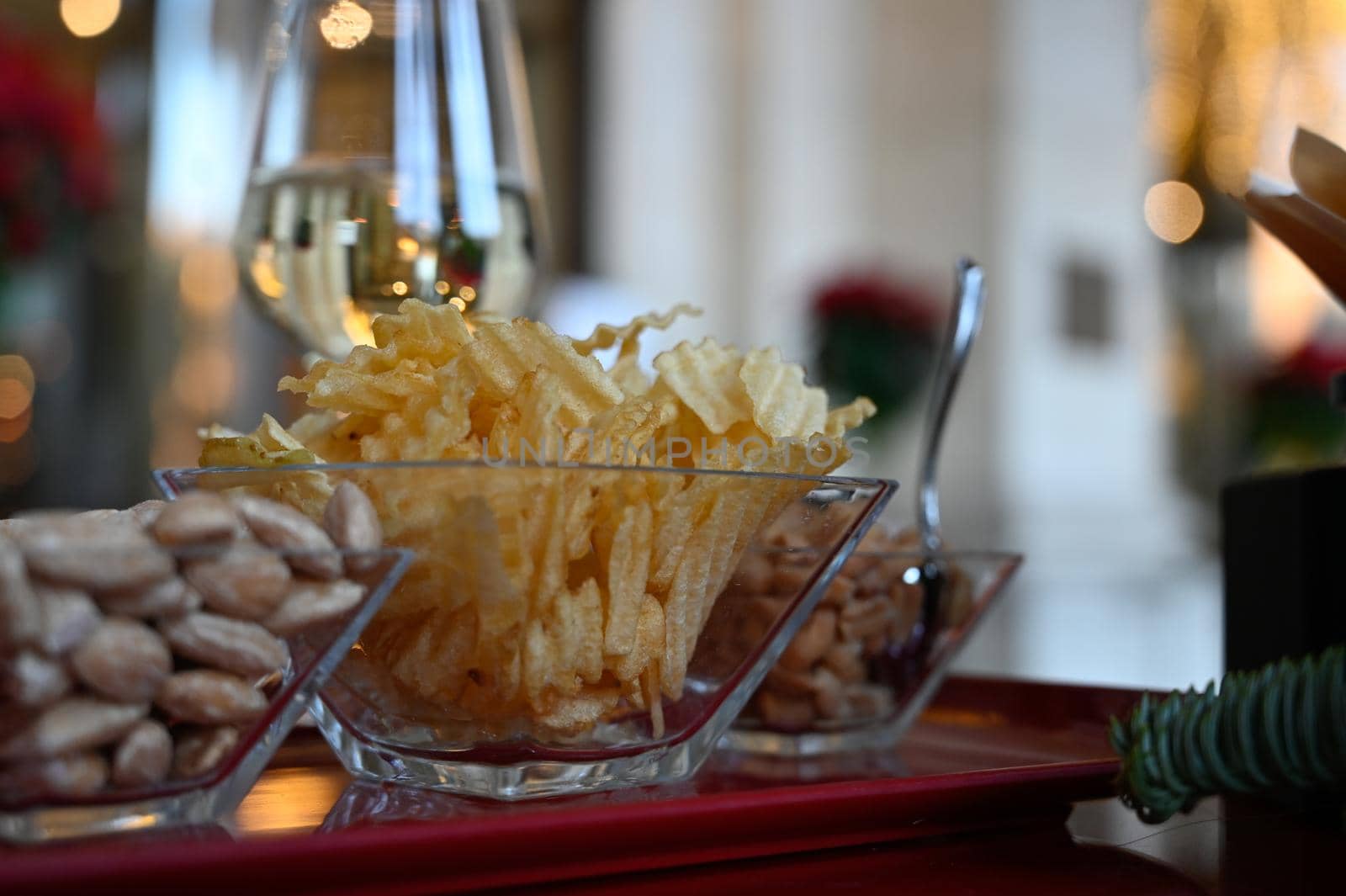 Some potato chips and nuts with wine glass on a restaurant table.