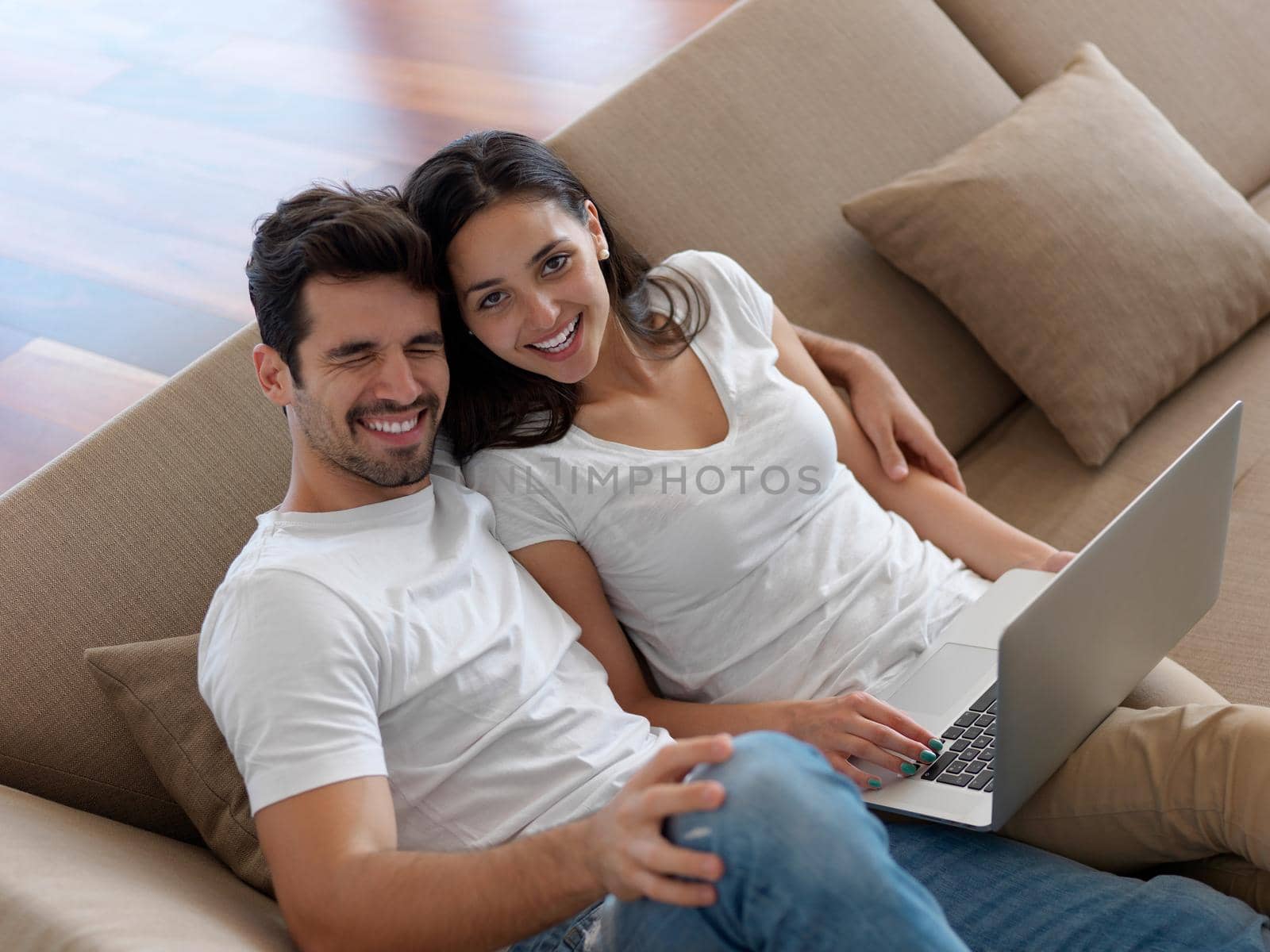 happy young relaxed  couple working on laptop computer at modern home indoor