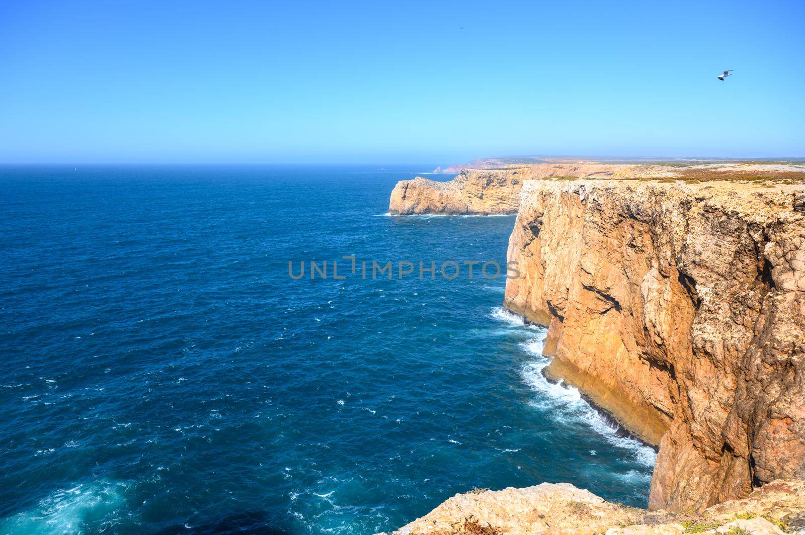 A beach with high rough cliffs at the Algarve in Portugal with some powerful waves.