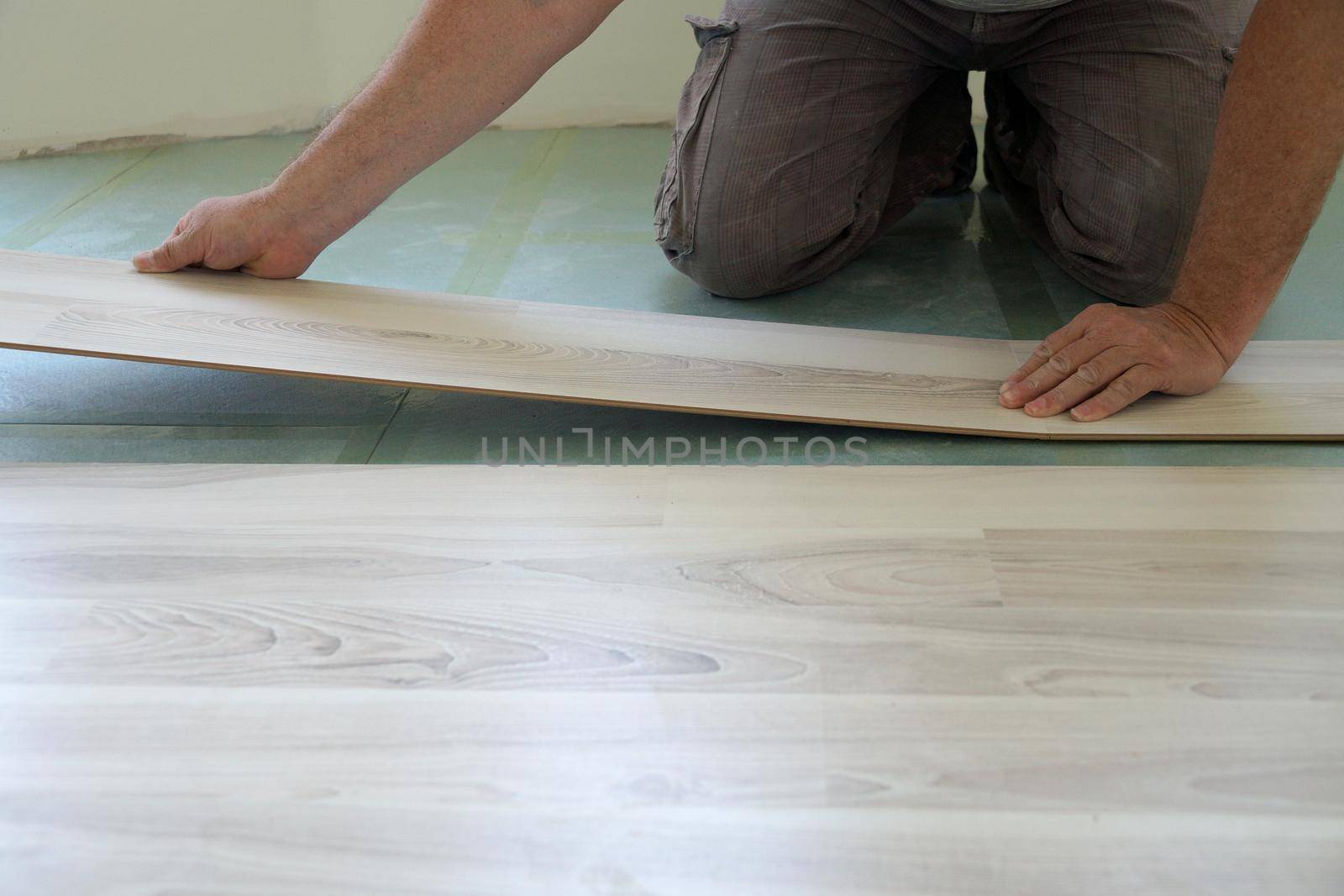a worker assembles a laminate floor in a living room close-up