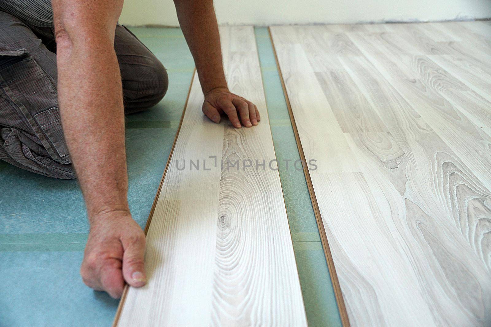 a worker assembles a laminate floor in a living room close-up