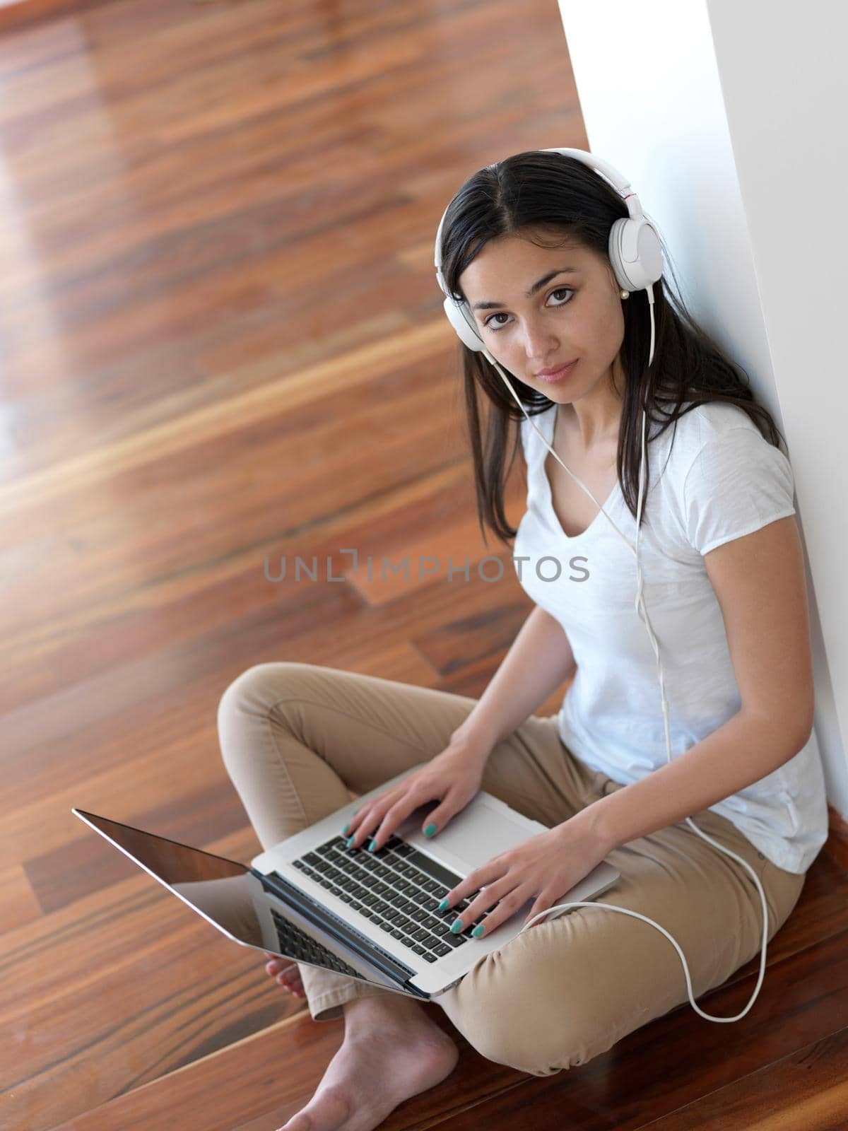 beautiful young woman relax and work on laptop computer modern  home office while listening musin on white headphones