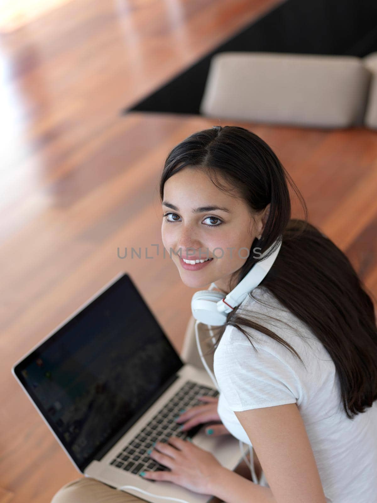 beautiful young woman relax and work on laptop computer modern  home office while listening musin on white headphones