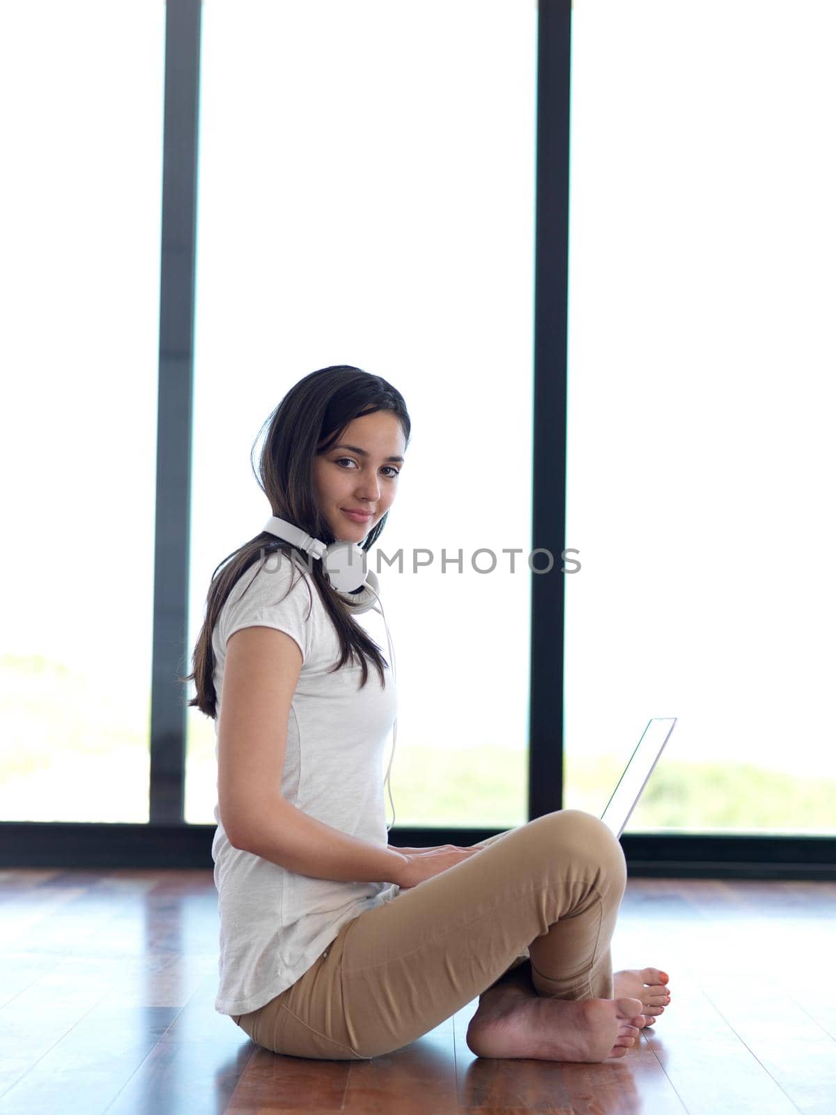 beautiful young woman relax and work on laptop computer modern  home office while listening musin on white headphones
