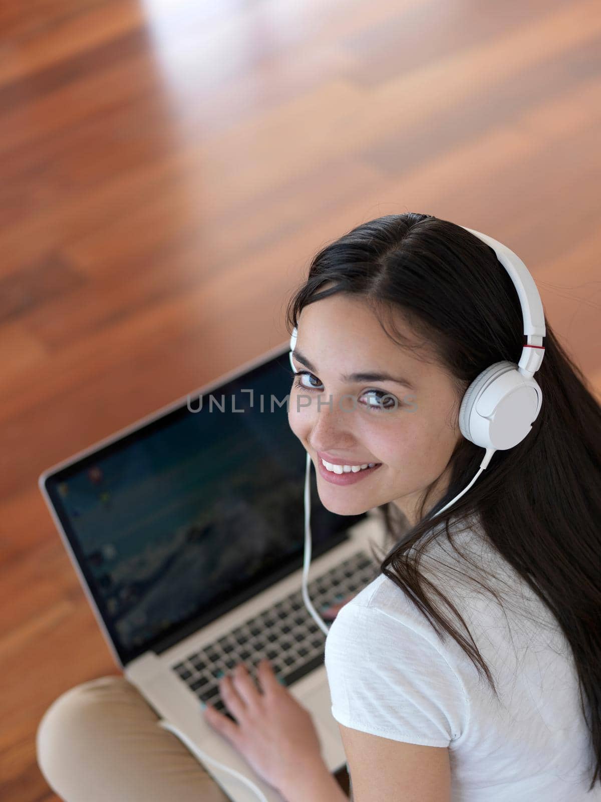 beautiful young woman relax and work on laptop computer modern  home office while listening musin on white headphones