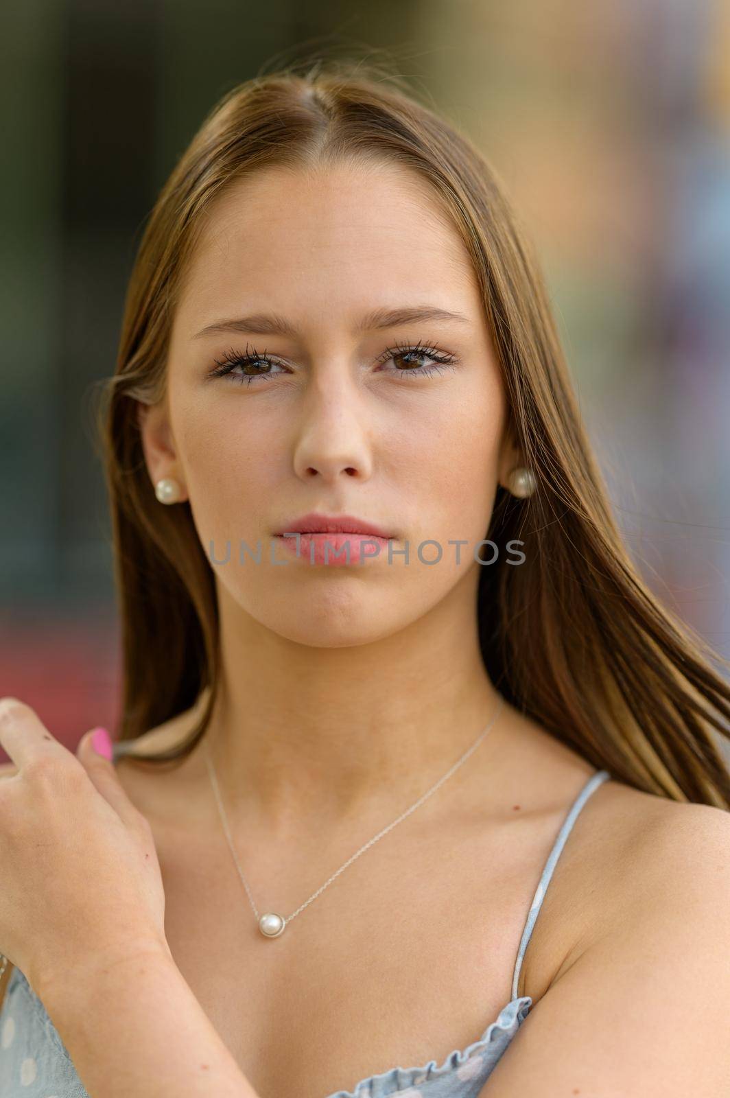 A portrait of a pretty young woman taken in the summertime in a city with a blurred background.