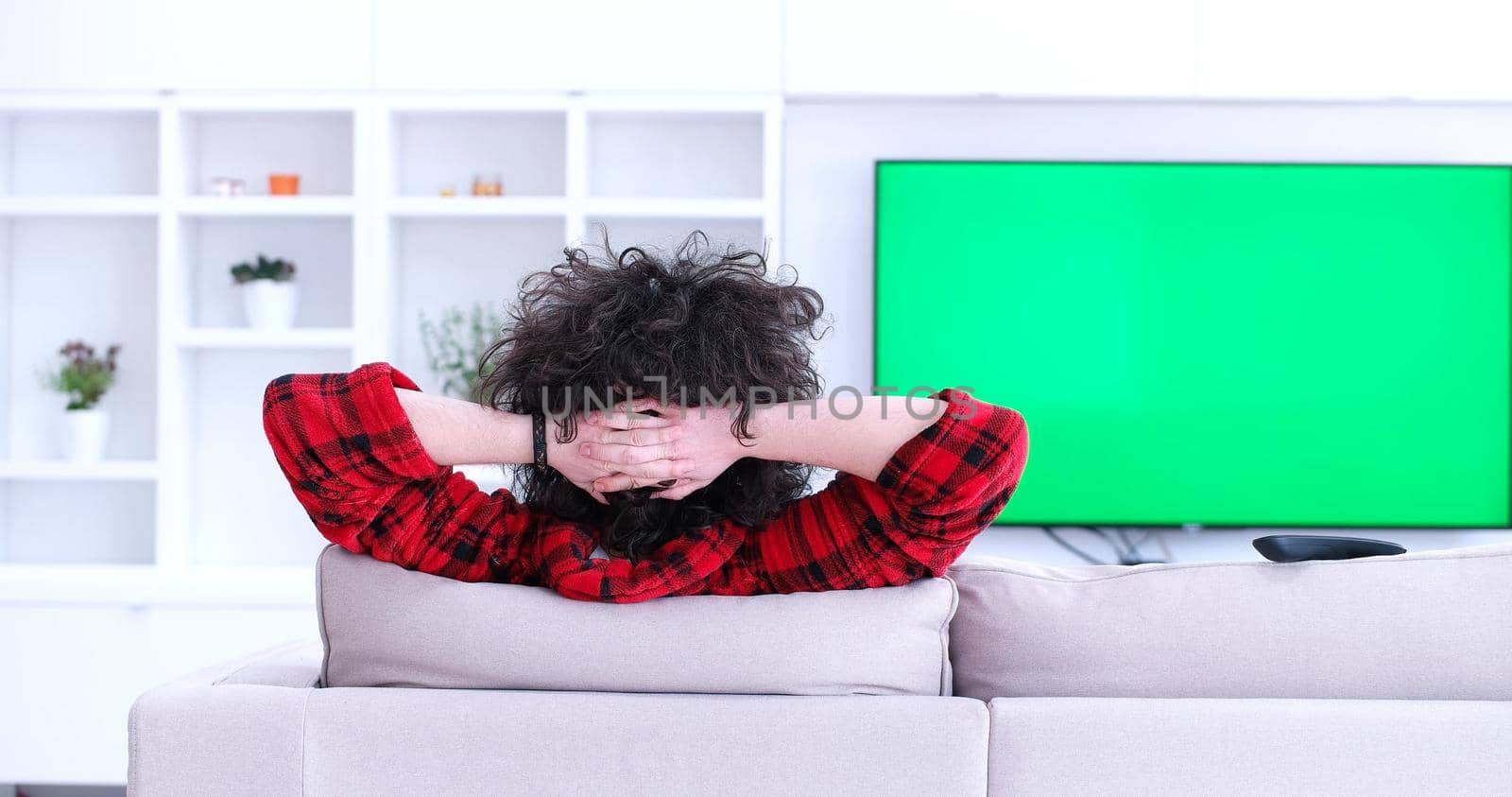 young handsome man enjoying free time watching television in his luxury home villa