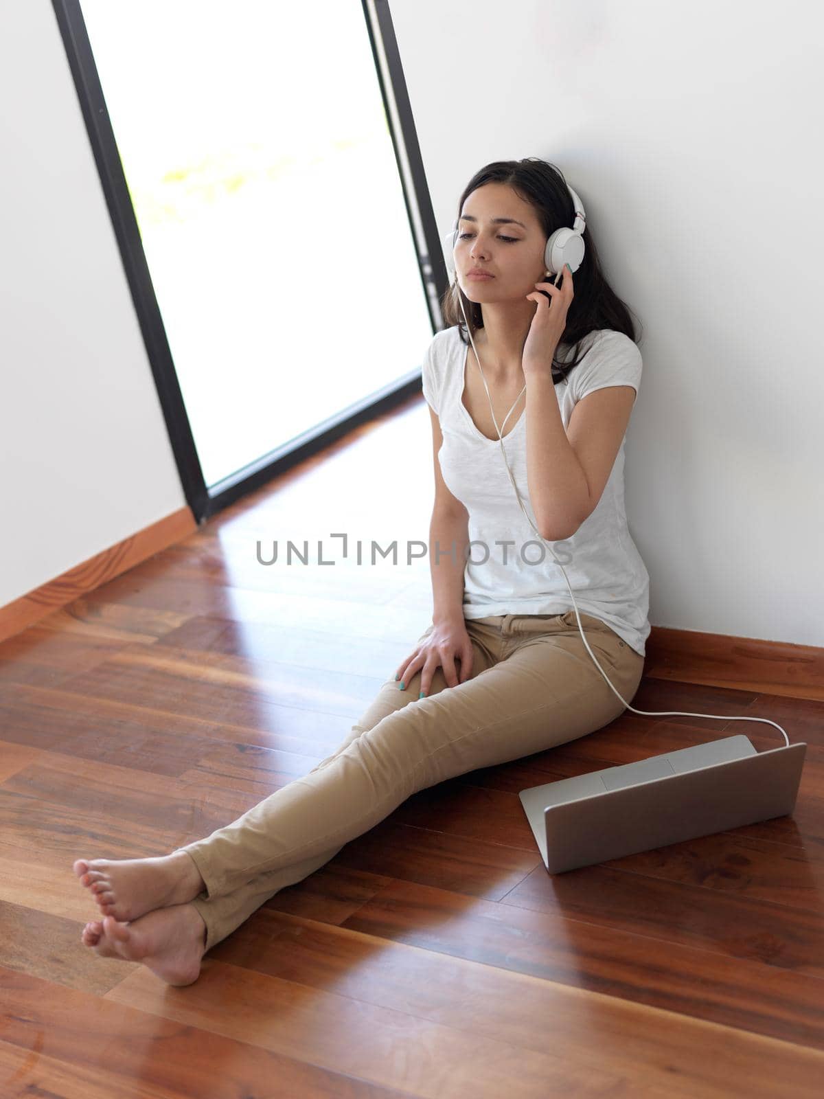 beautiful young woman relax and work on laptop computer modern  home office while listening musin on white headphones