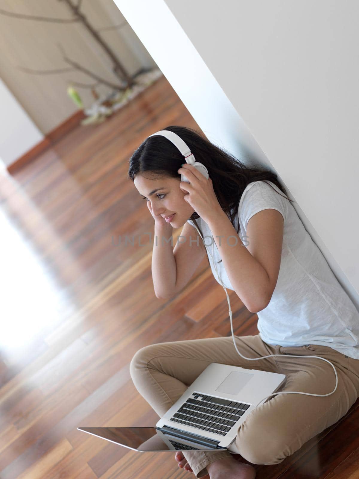 beautiful young woman relax and work on laptop computer modern  home office while listening musin on white headphones