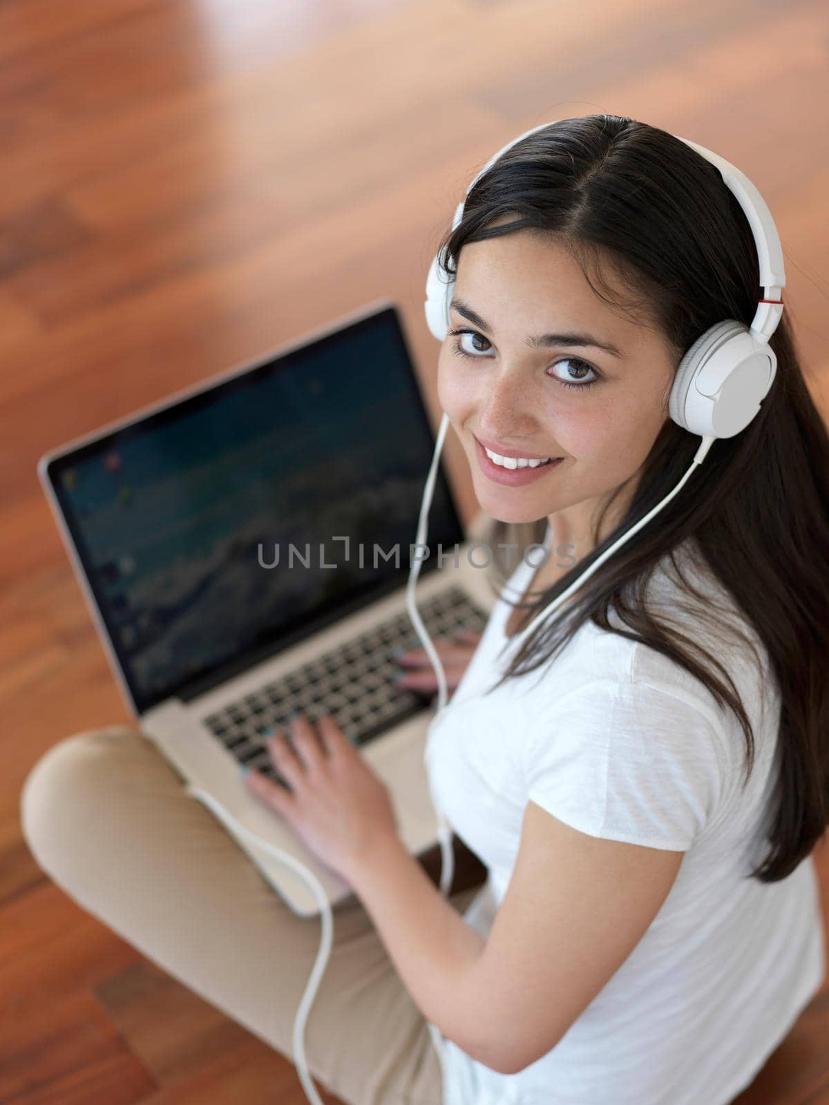 beautiful young woman relax and work on laptop computer modern  home office while listening musin on white headphones