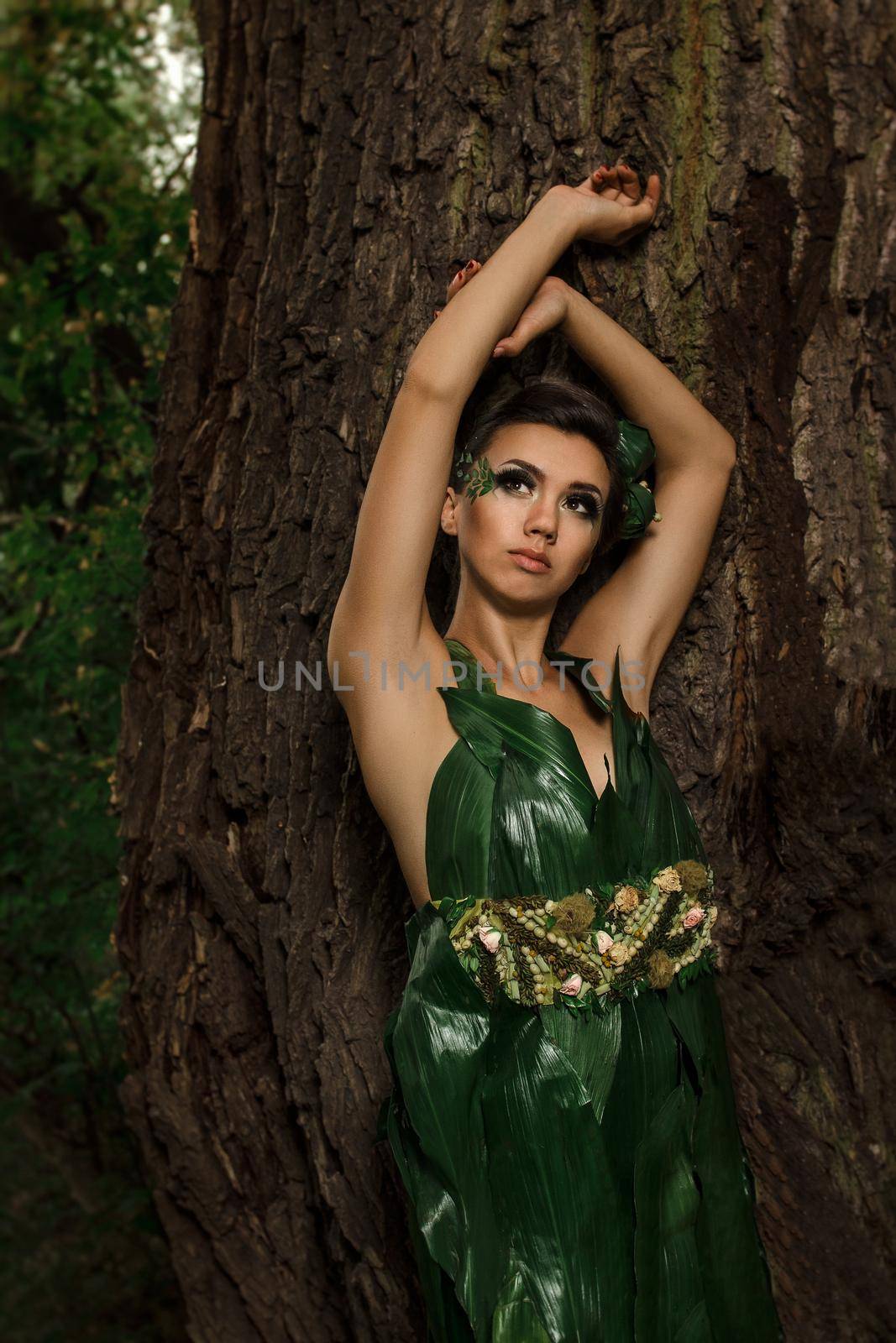 girl in a dress of green palm leaves on a forest lake