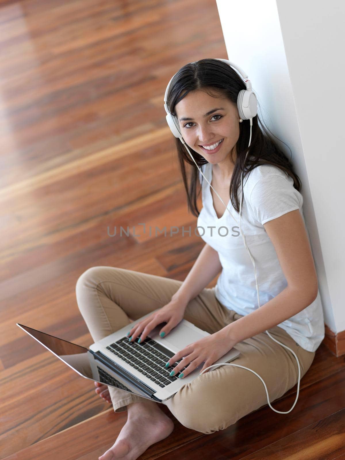 beautiful young woman relax and work on laptop computer modern  home office while listening musin on white headphones